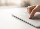 Close-up of a fingertip confirming an action on a laptop trackpad.