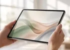 Close-up of a tablet held in both hands in a bright office.
