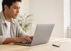 A professional at a laptop with a security key resting on the desk.