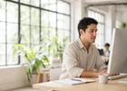 A man working at a desktop computer in a bright coworking space.