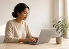 A young freelancer working on a laptop in a sunlit minimalist apartment.