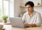 A young entrepreneur invoicing from a laptop at the kitchen table.