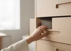 Close-up of a hand opening one of several filing drawers in a bright office.