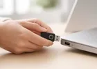Close-up of hands plugging a USB security key into a laptop.