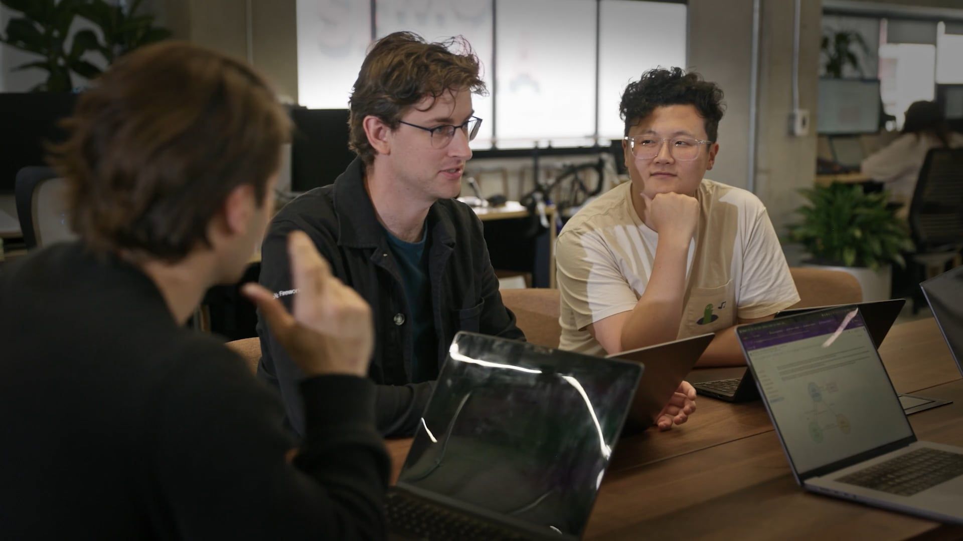 Group talking at conference table with laptops