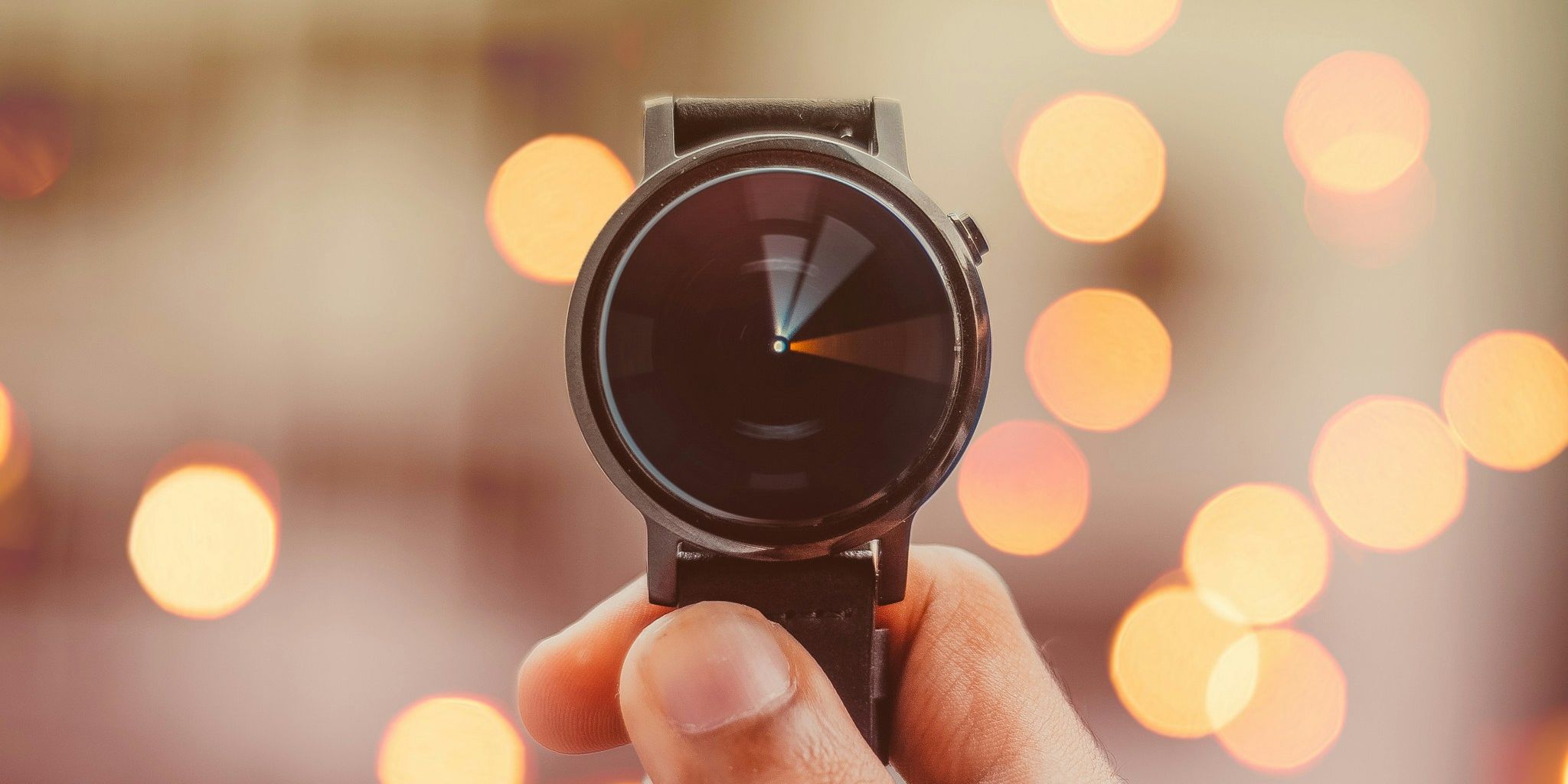 a person is holding a watch in front of a blurry background of lights .