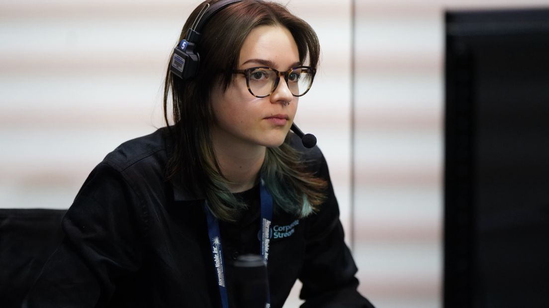 Emmy looks at a computer monitor while operating multiple cameras
