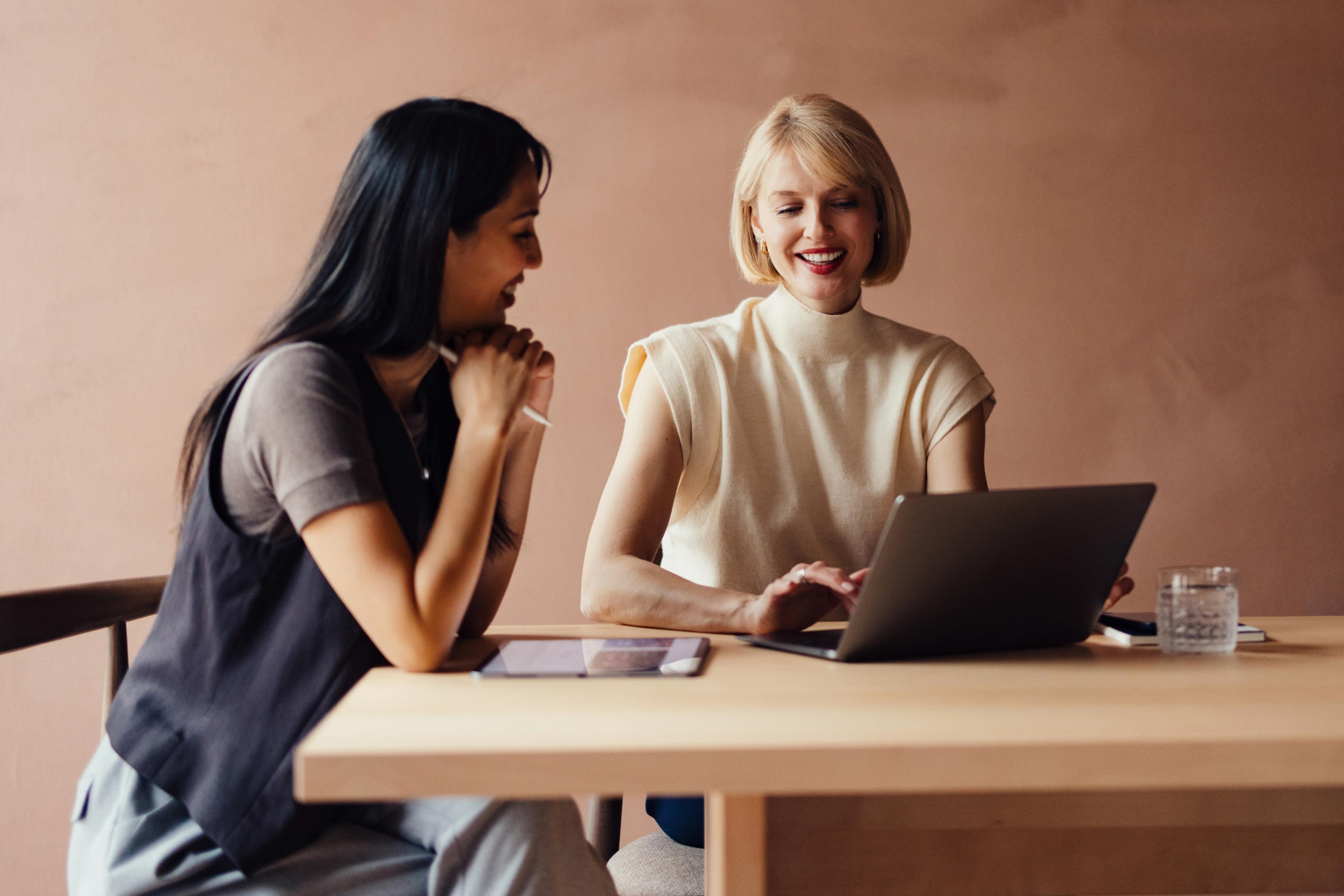 Two professionals collaborating while researching HR compliance software.