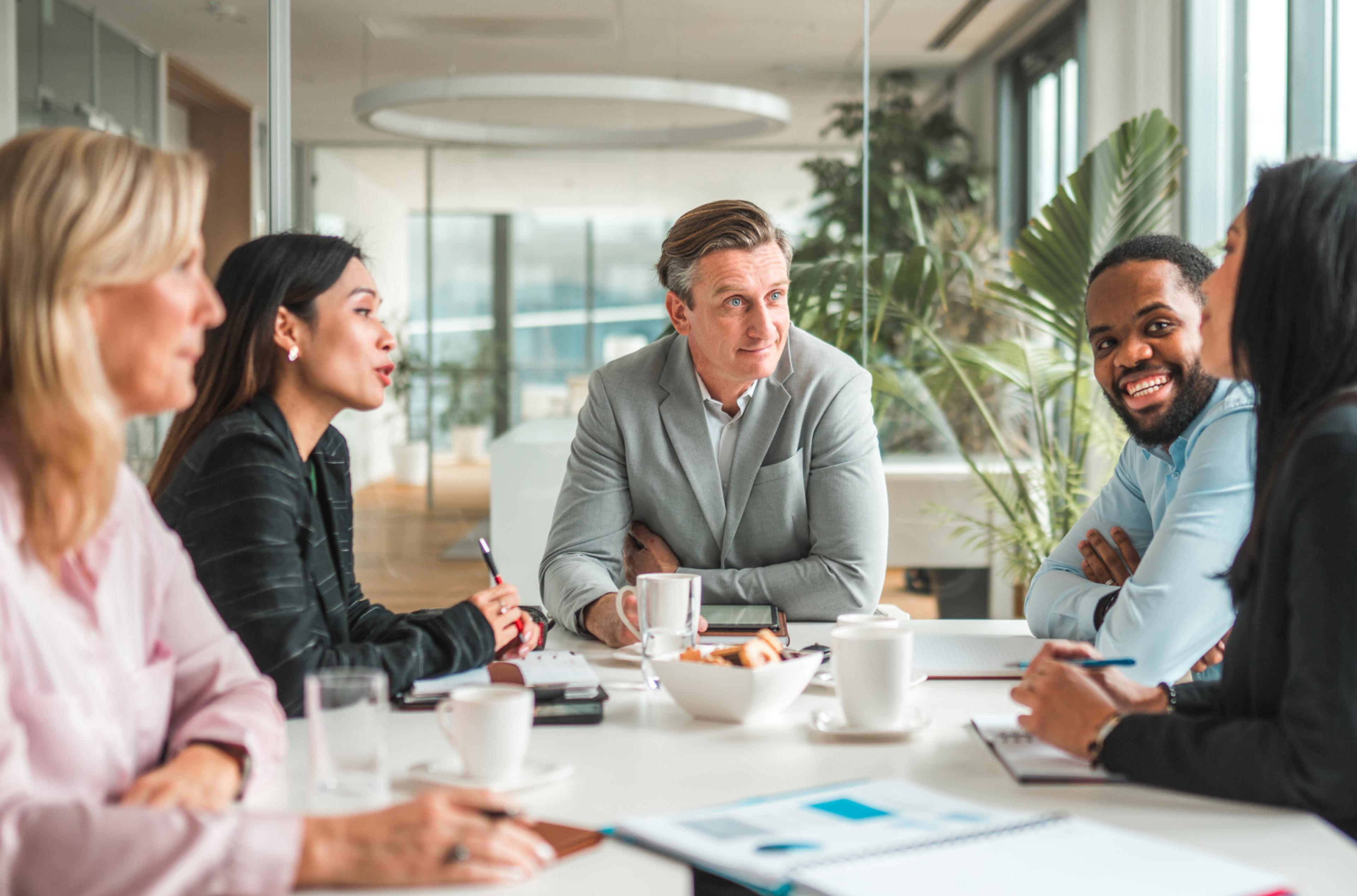 Group of HR leaders discuss the latest industry news around a boardroom table