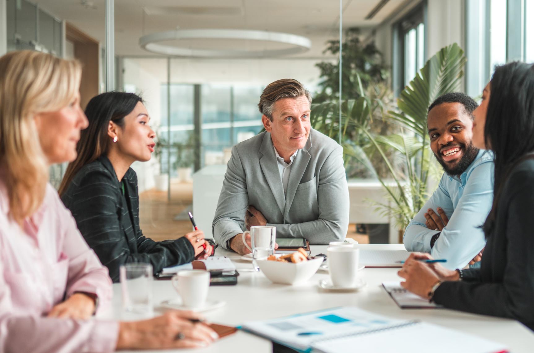 Group of HR leaders discuss the latest industry news around a boardroom table