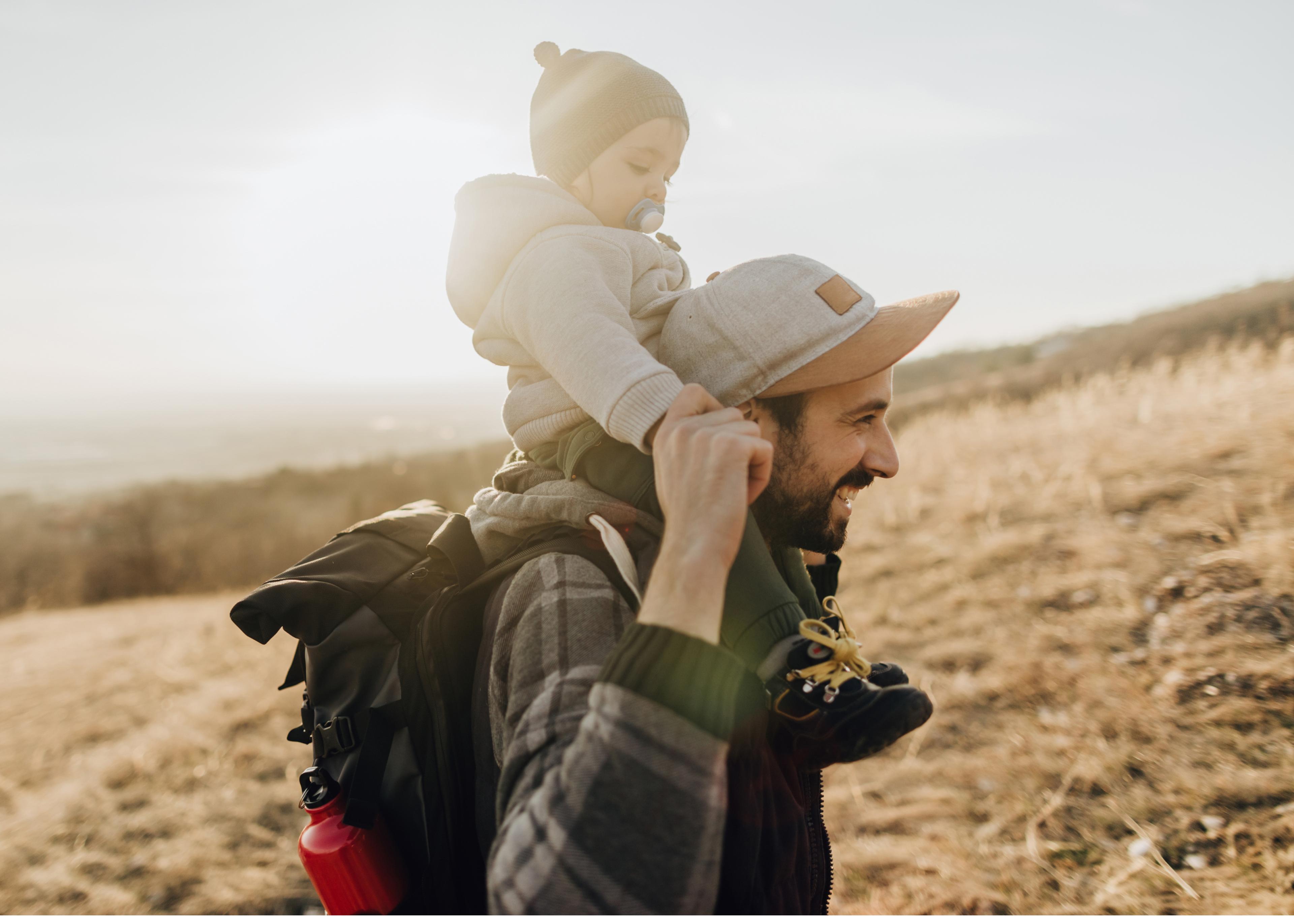 Father hiking with his kid on his shoulders.