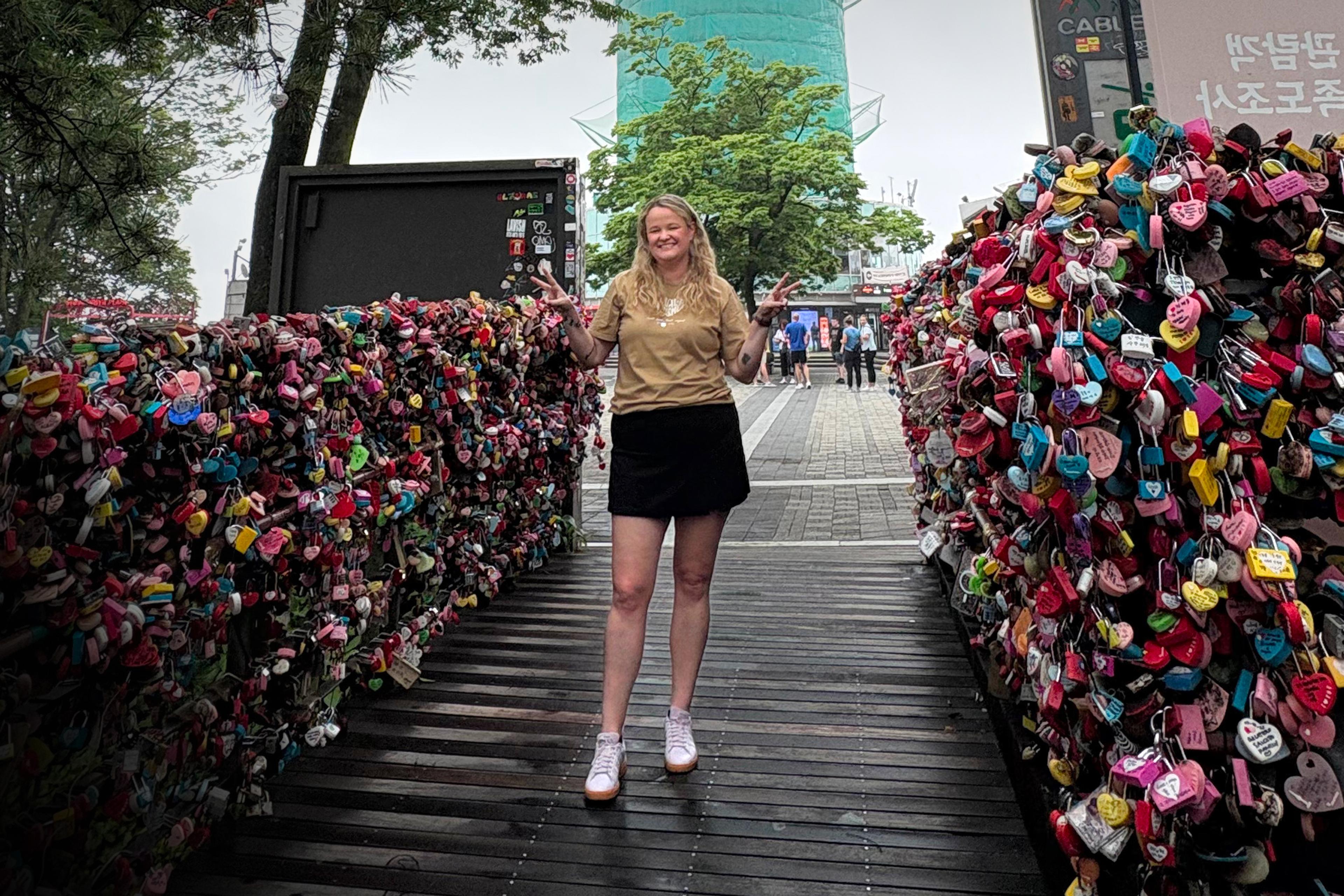 Ana Elisa Berardo stands between two walls densely covered in colorful love locks.