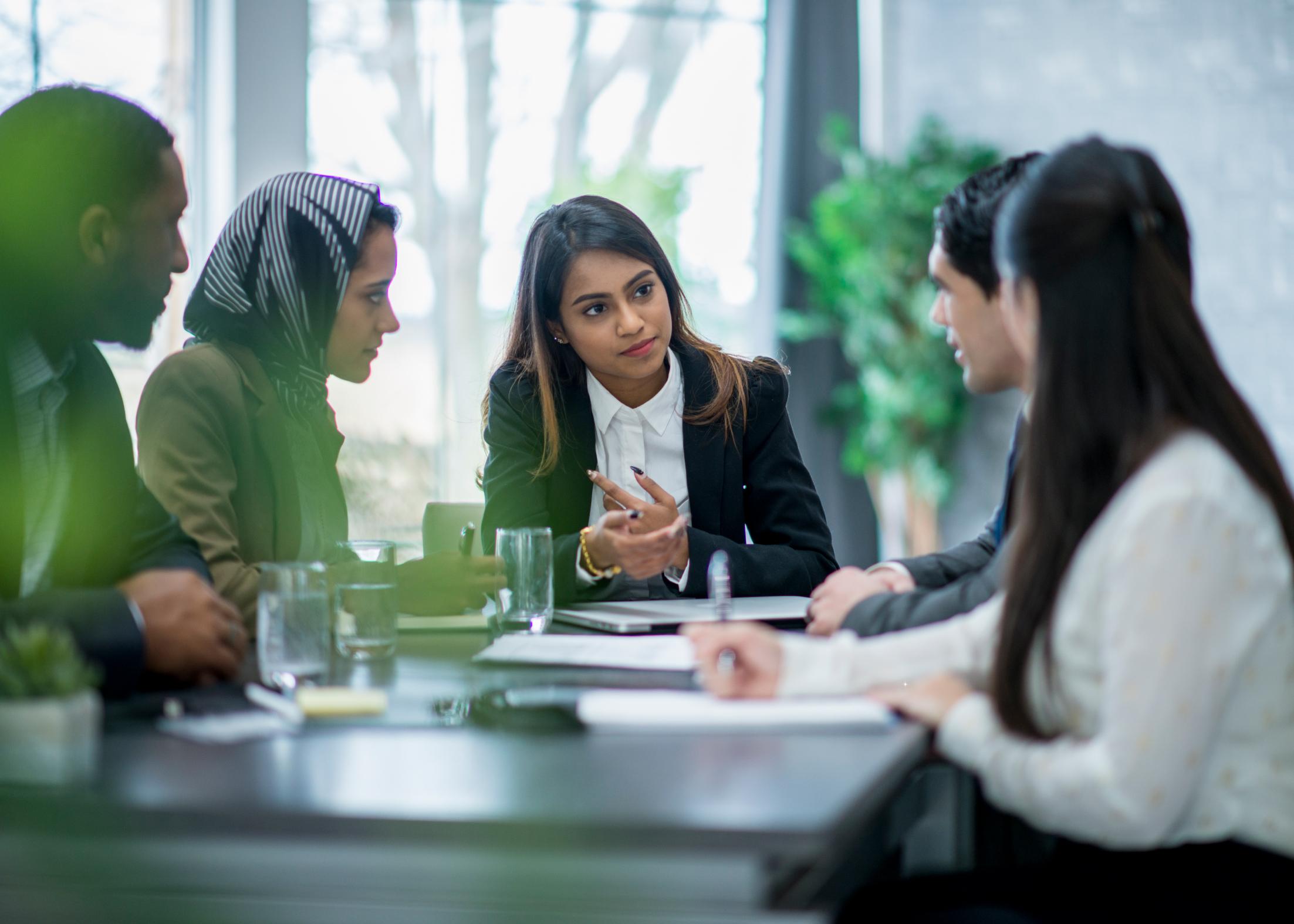 A small legal team sitting in a conference room discussing international business law and considerations for expanding their business abroad