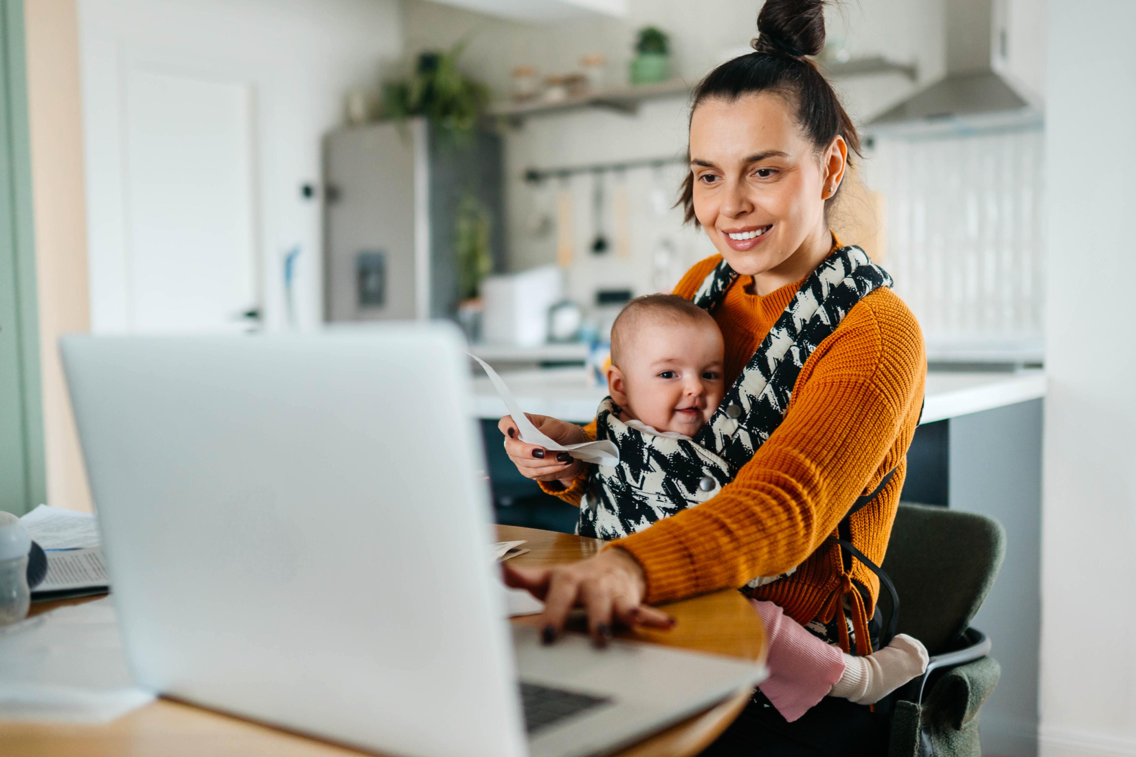 Woman working from home while caring for a baby during maternity leave in France.