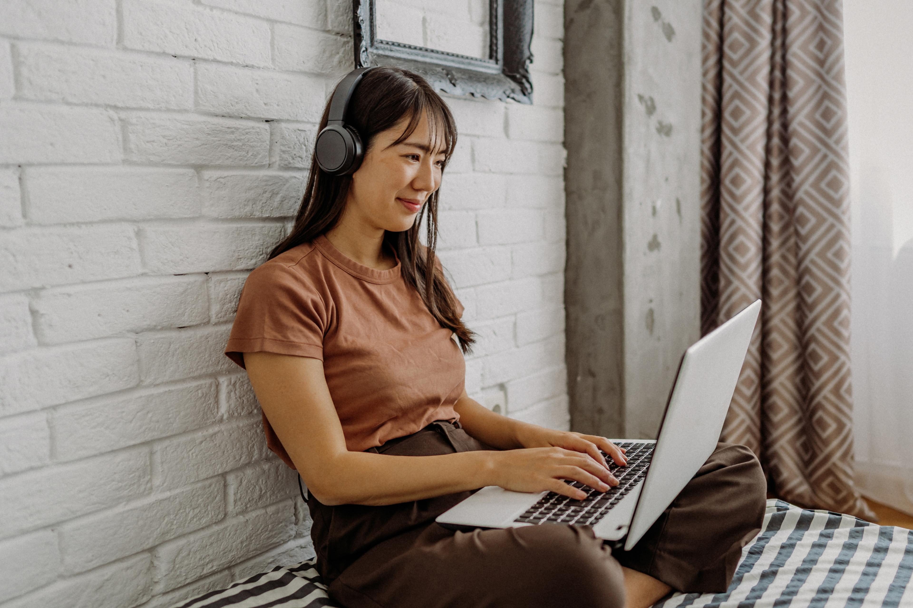 Woman working from home on a laptop while wearing headphones