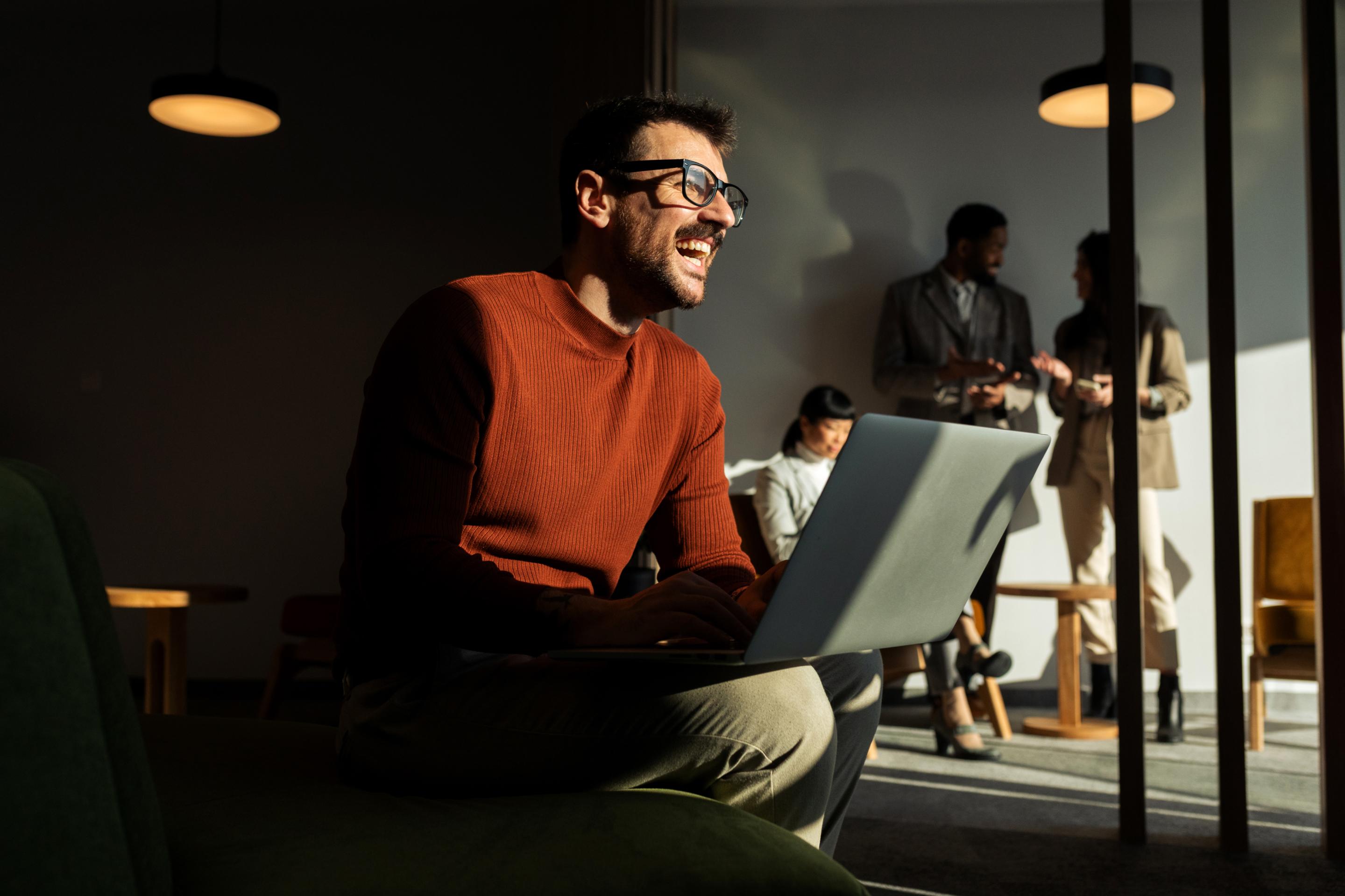 Man working on a laptop in an office lounge, representing a typical earner of the average salary in Portugal.