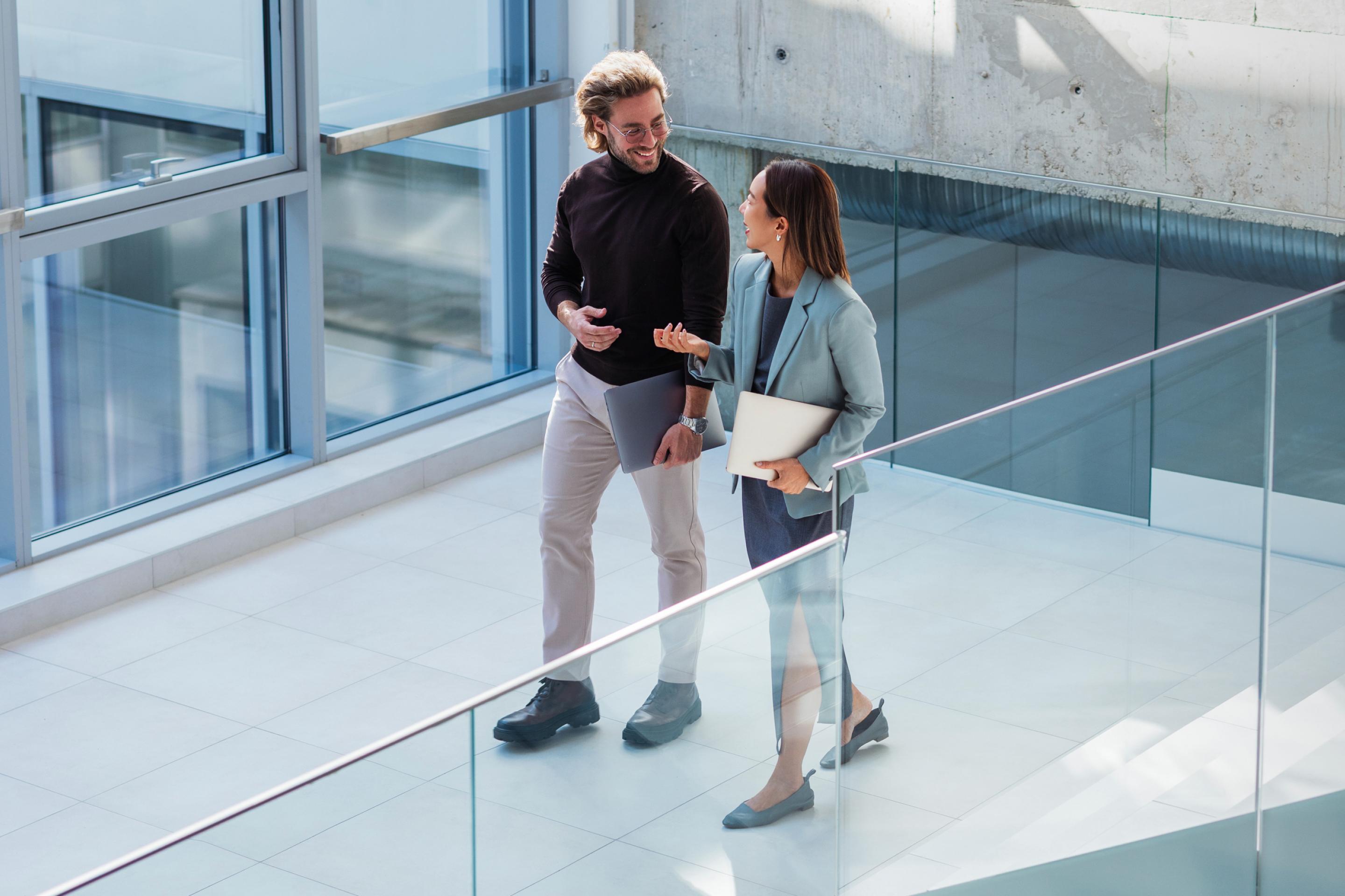 Two colleagues discussing payroll data while walking through a modern office, representing employers researching the average salary in Costa Rica.