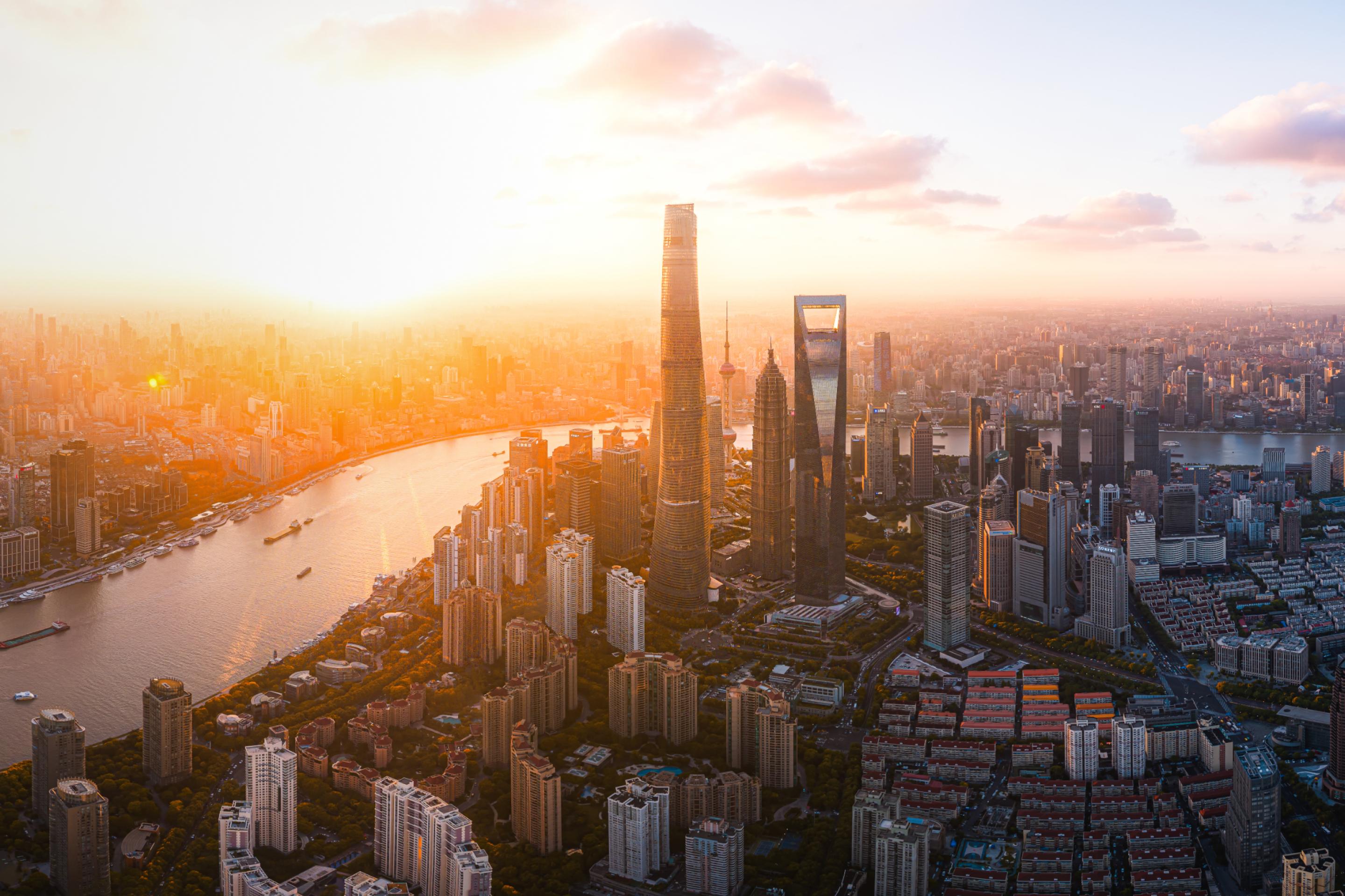 Aerial view of Shanghai's cityscape and Huangpu River at golden hour.