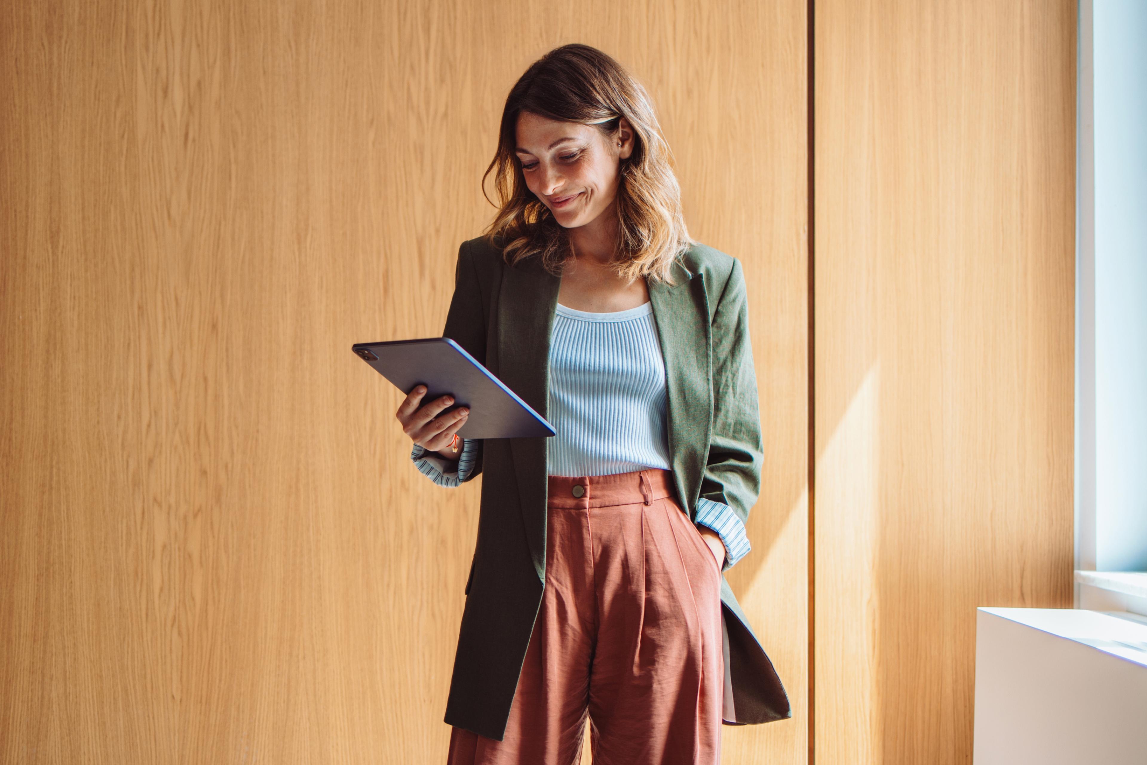 Businesswoman smiling while holding a tablet, discovering the average salary in Poland.