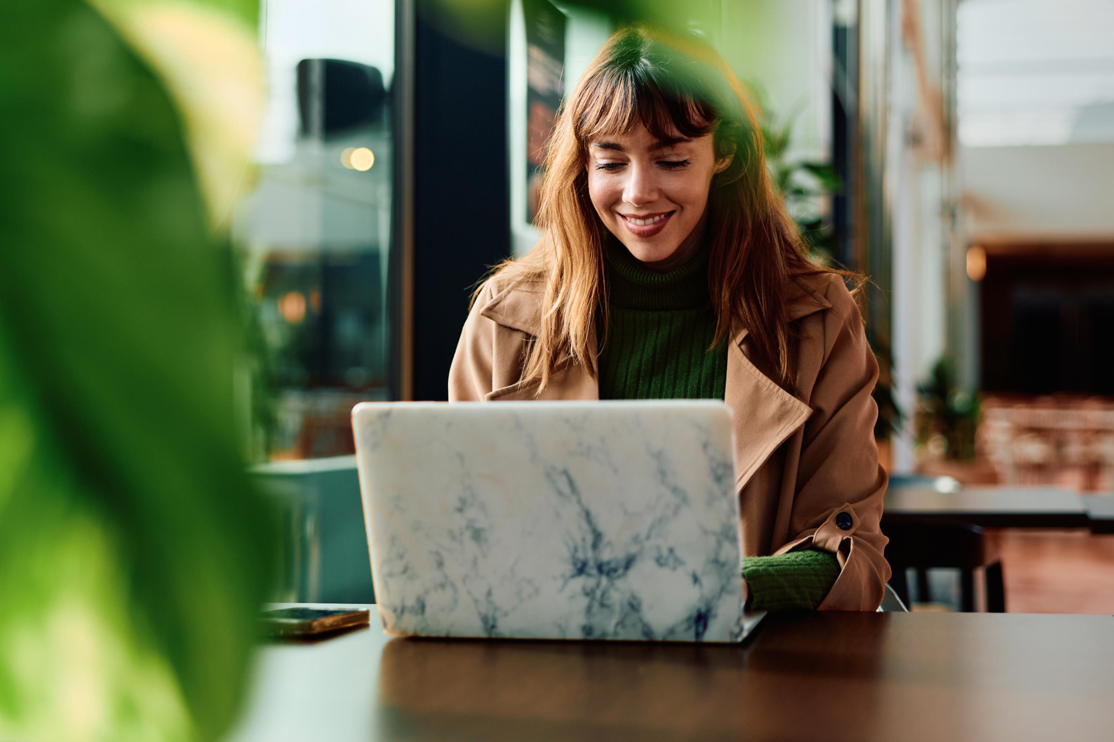 Smiling woman using a laptop in a cafe.