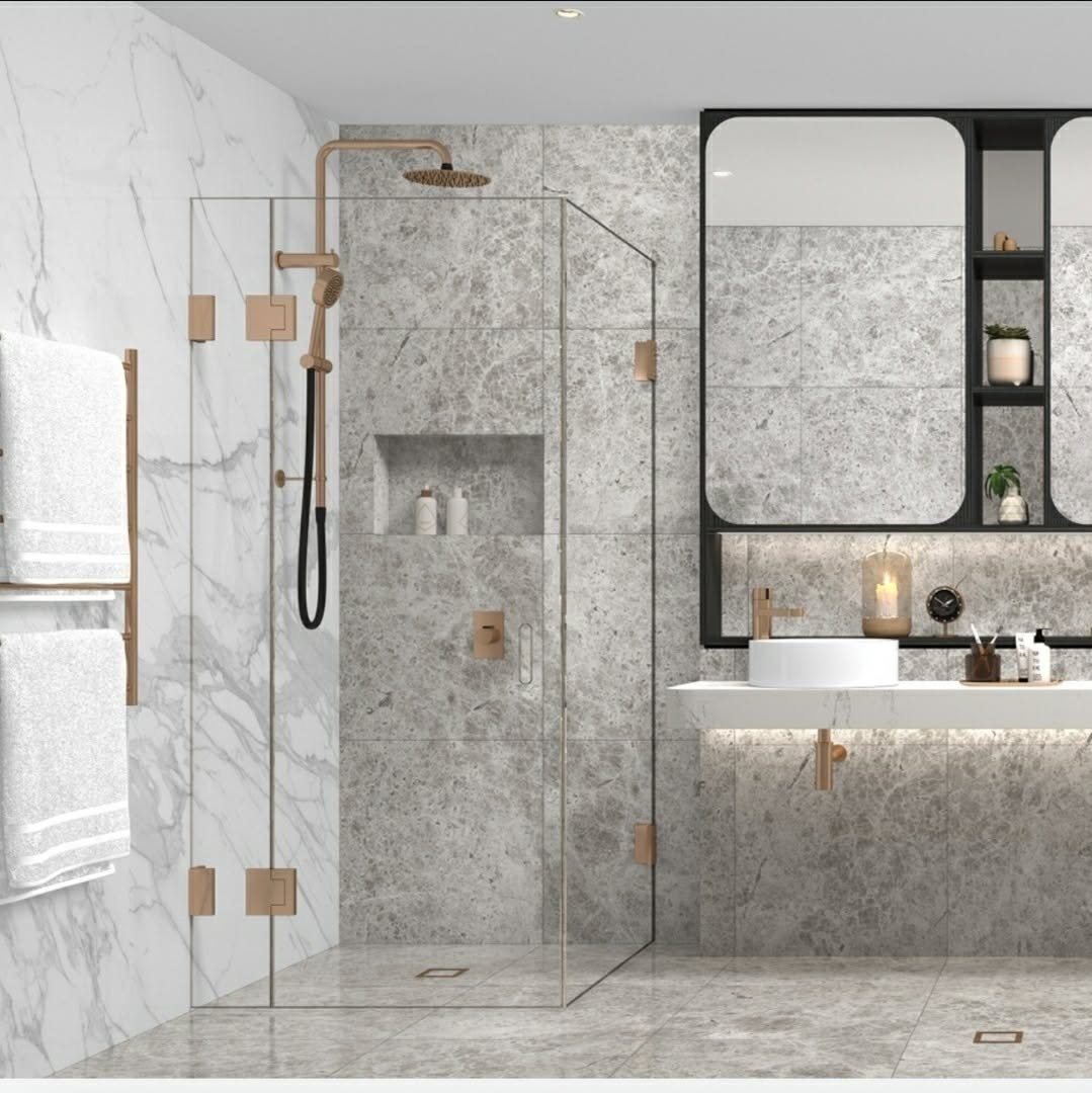 A marble ensuite with a frameless glass shower, recessed niche and brushed brass fittings