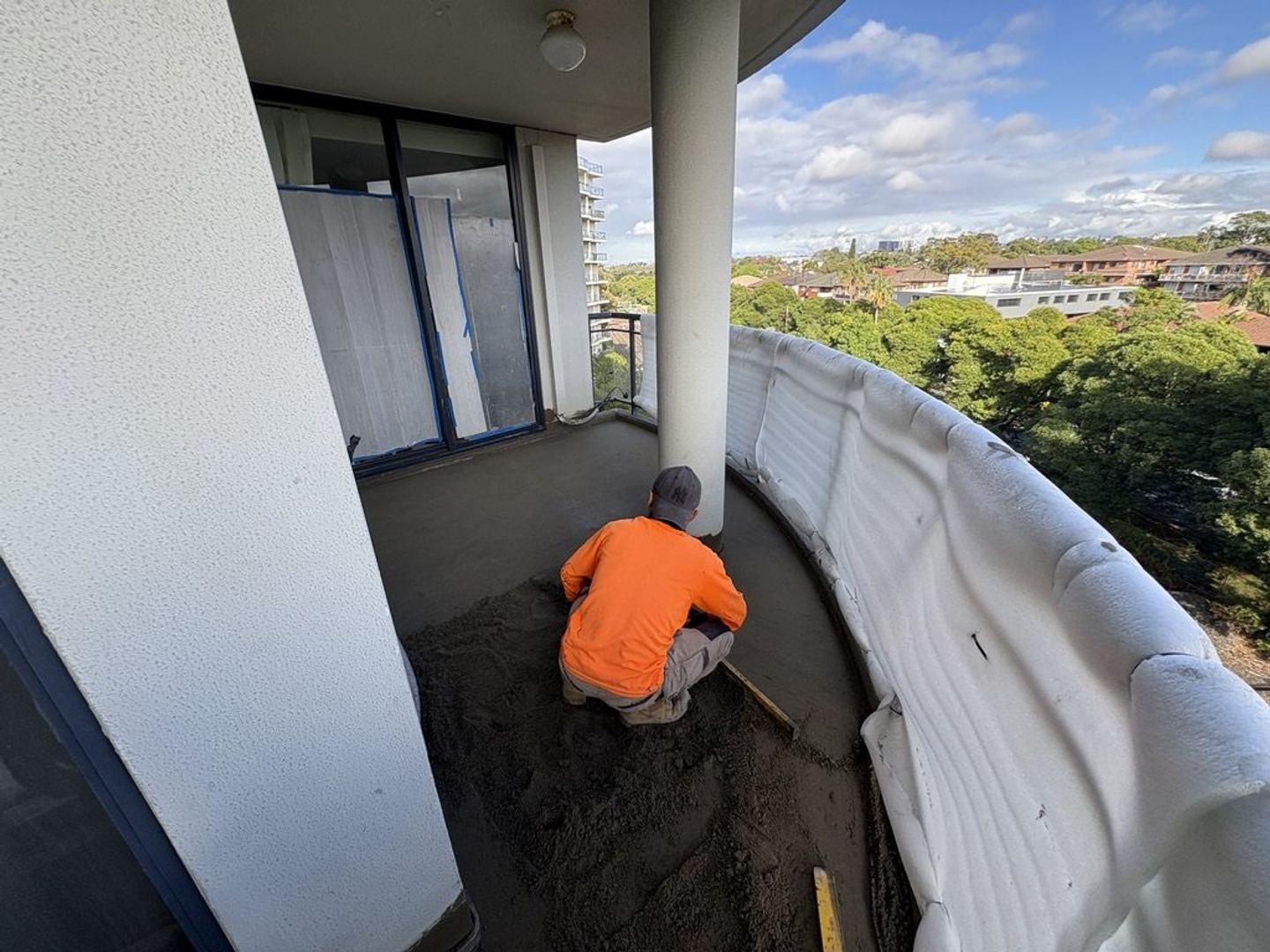 A tradesman screeding to falls on a curved balcony above the treeline