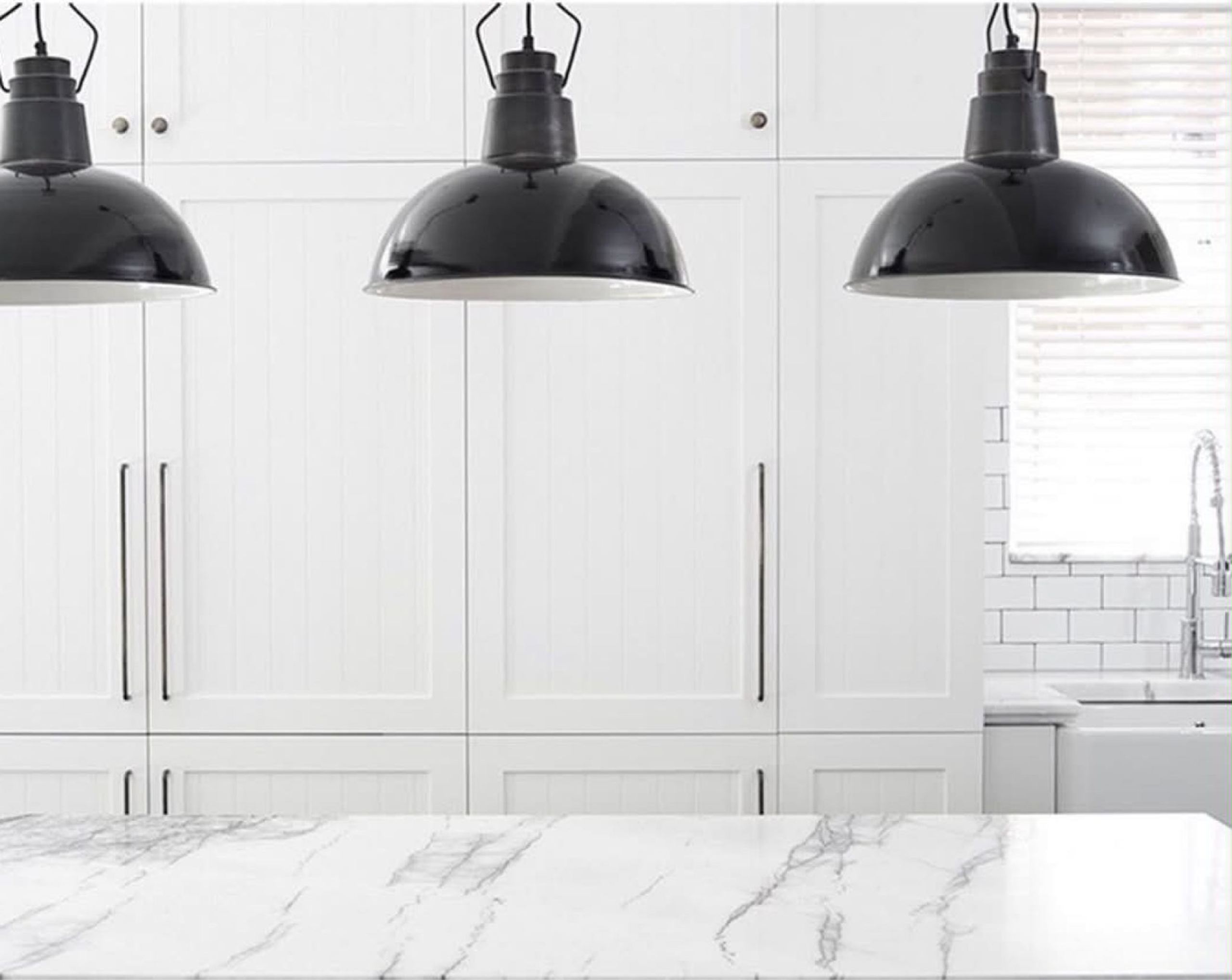 The Woollahra apartment kitchen in white joinery and marble under black pendant lights