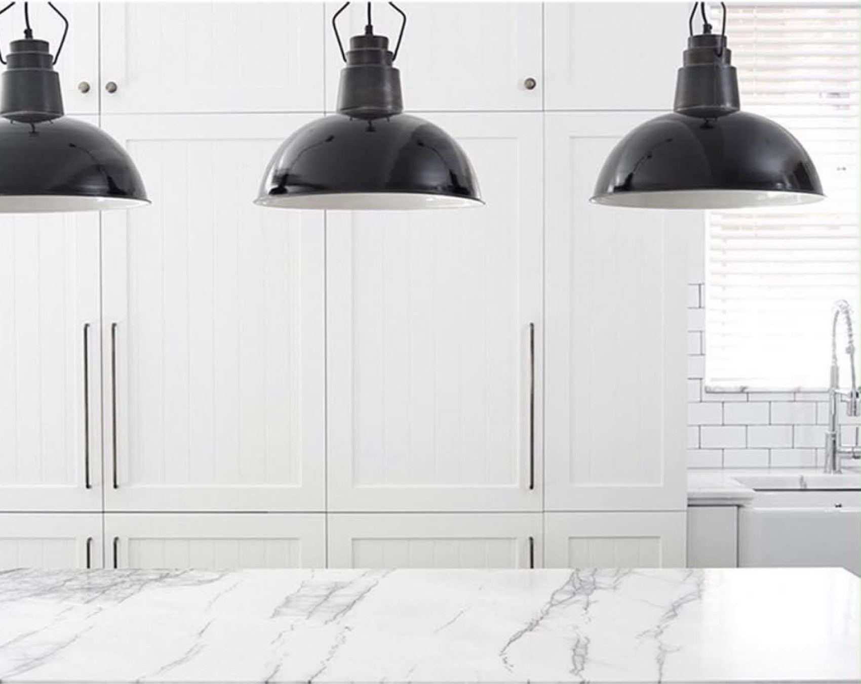 The Woollahra apartment kitchen in white joinery and marble under black pendant lights
