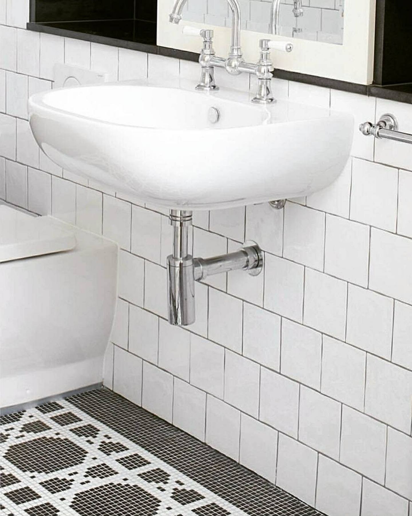 A wall-hung basin above a patterned encaustic tile floor laid to a border