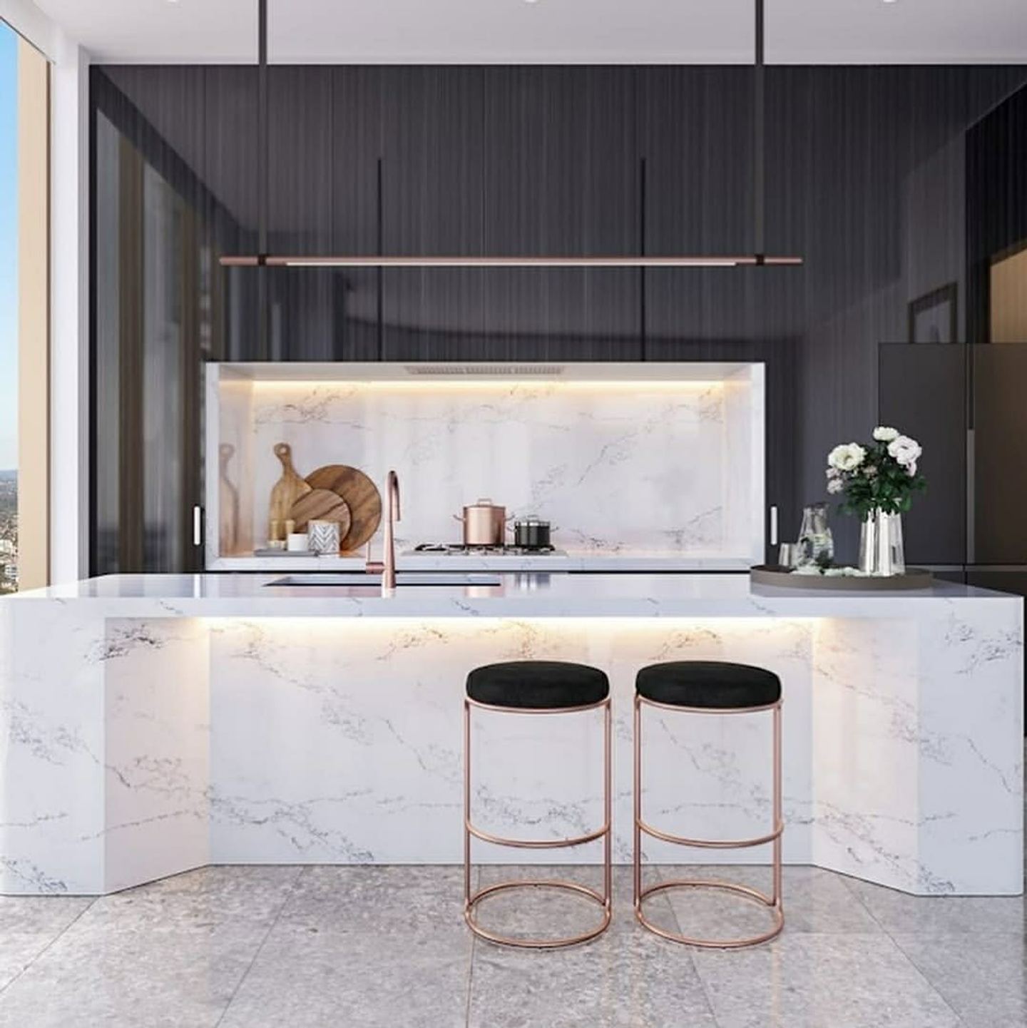 A marble kitchen with a waterfall island, brushed brass tapware and concealed lighting