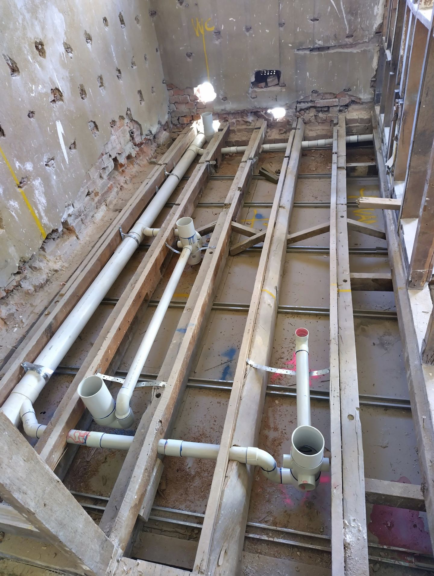 A bathroom floor opened up with new hydraulic services roughed in between the joists