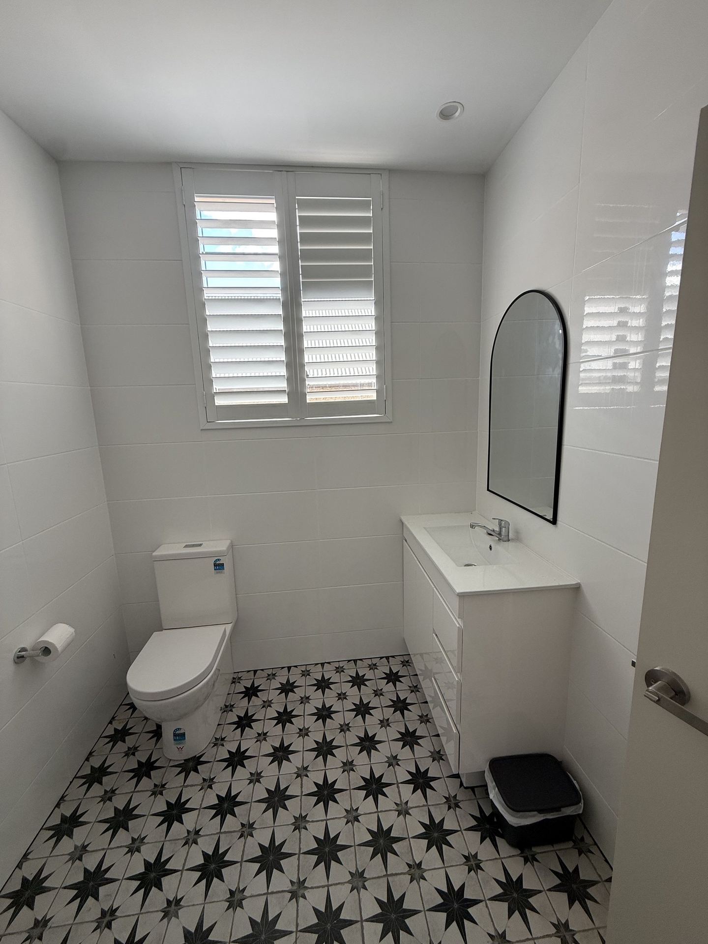 A completed apartment bathroom in white joinery over a patterned encaustic floor