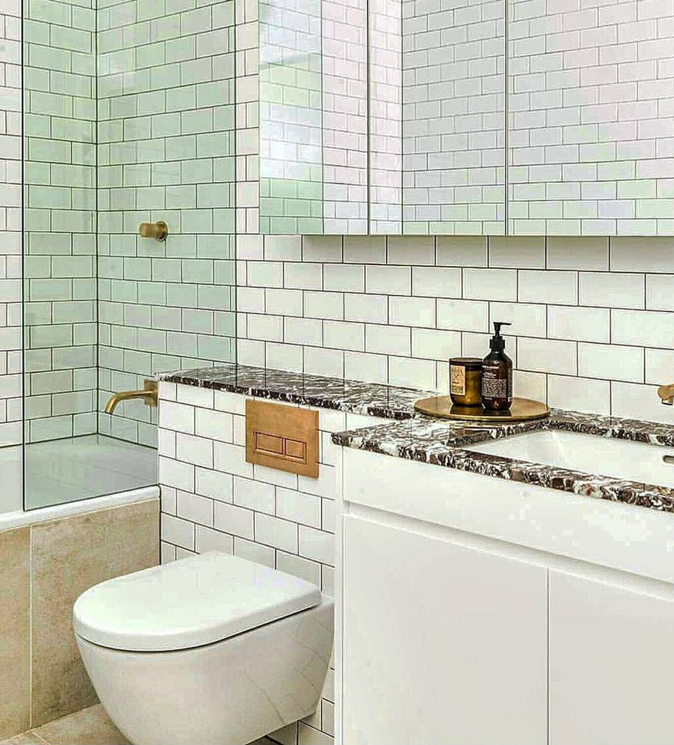 The renovated Mosman bathroom in subway tile with a stone vanity top and brass fittings