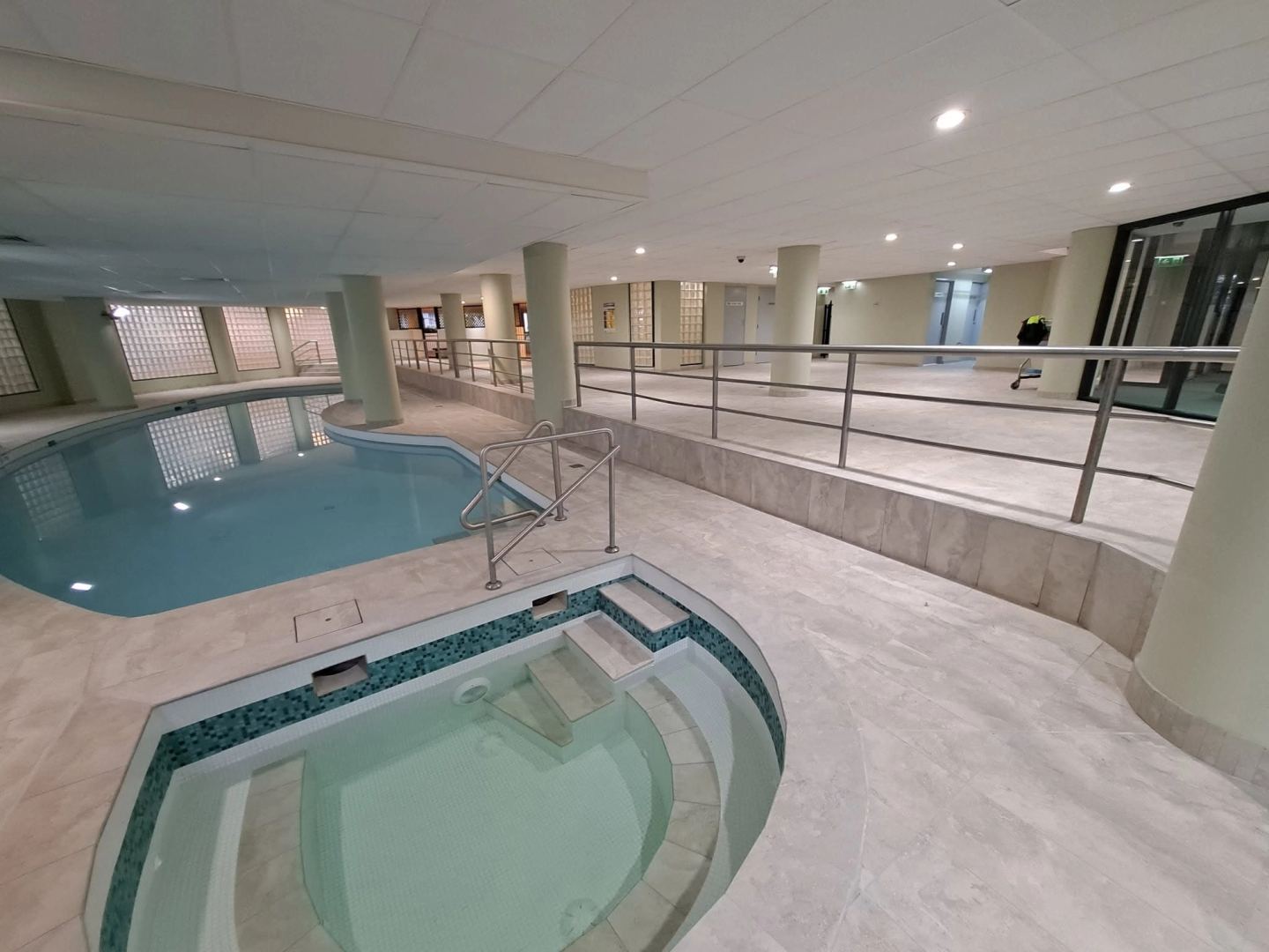 The finished pool and spa in pale stone tile with new stainless balustrading