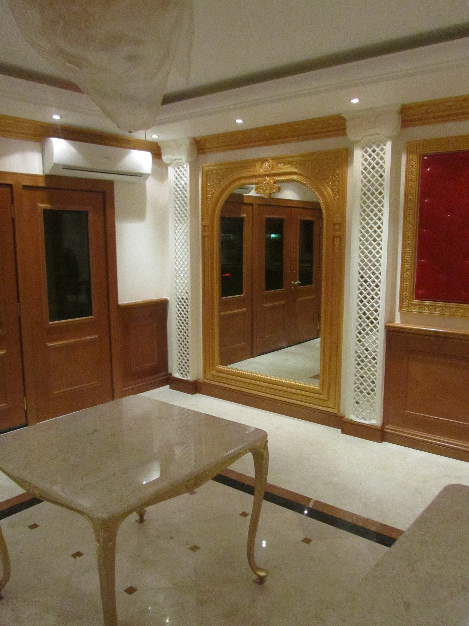 Hospitality interior with decorative timber wall panelling, mirror surround and marble flooring