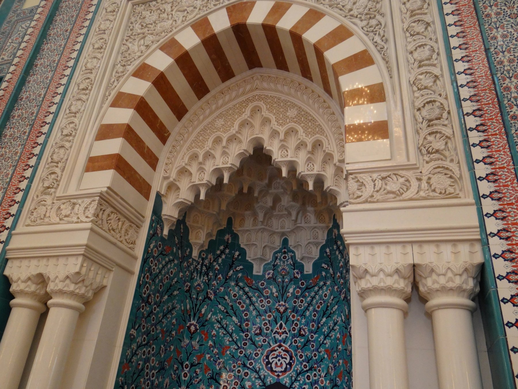Ornate mosque prayer niche with carved plaster and patterned ceramic detailing