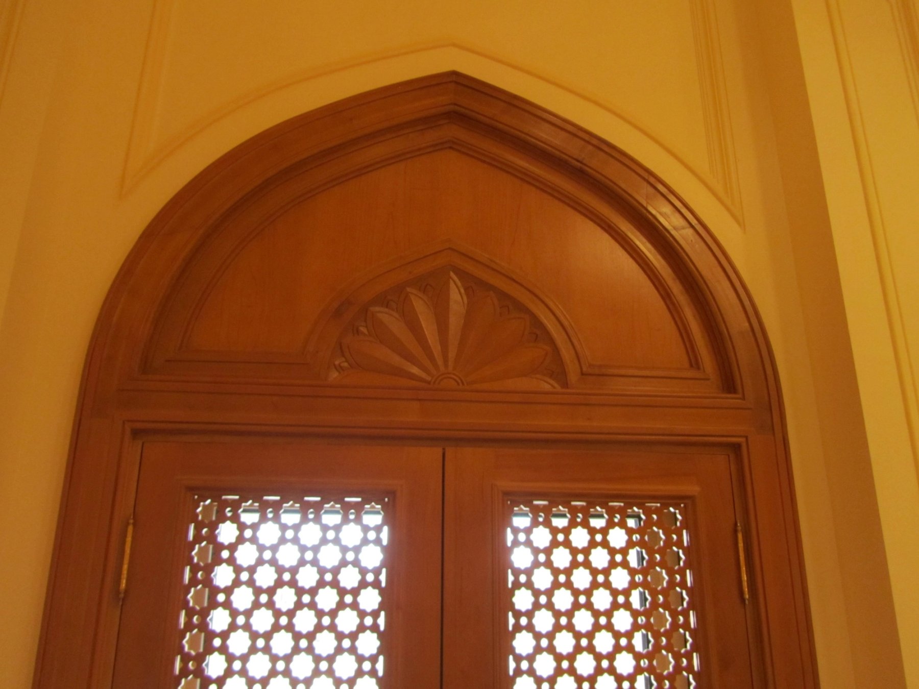Close-up of an arched timber lattice door with carved fanlight detailing