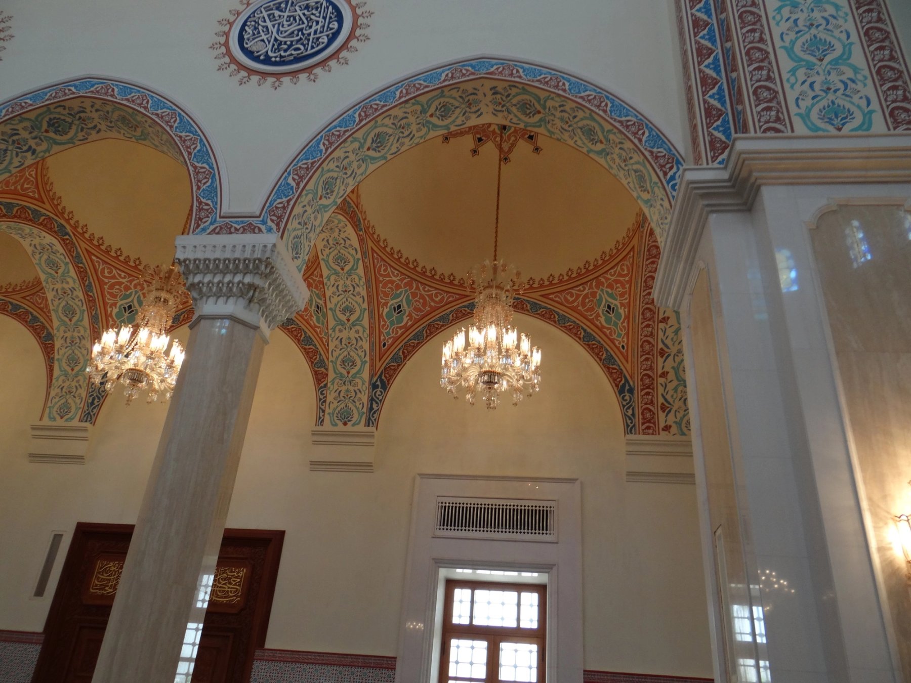 Painted mosque arches with chandeliers and decorative column detailing