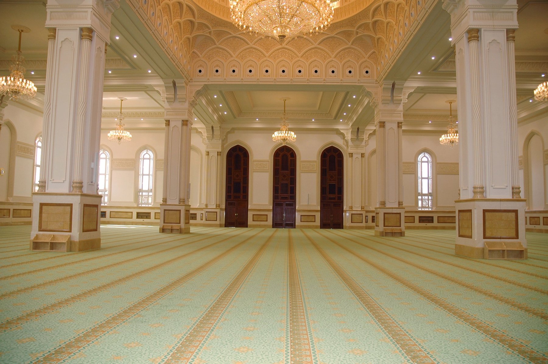 Ornate religious interior with decorative columns, chandeliers and patterned carpet