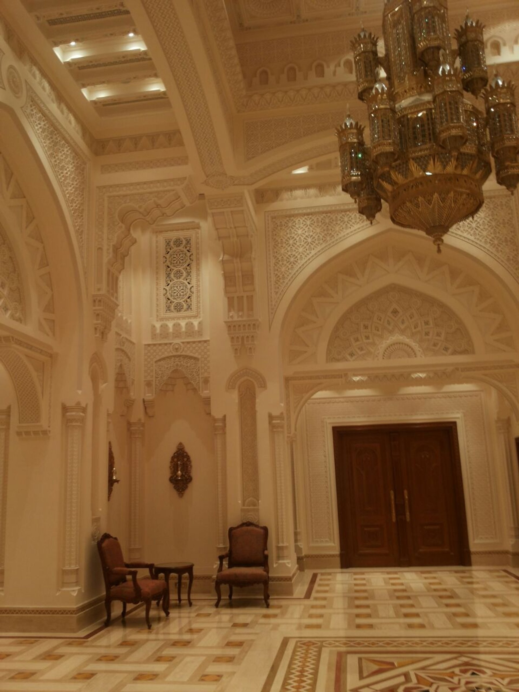 Decorative wall composition with arched niches, timber door and patterned marble flooring