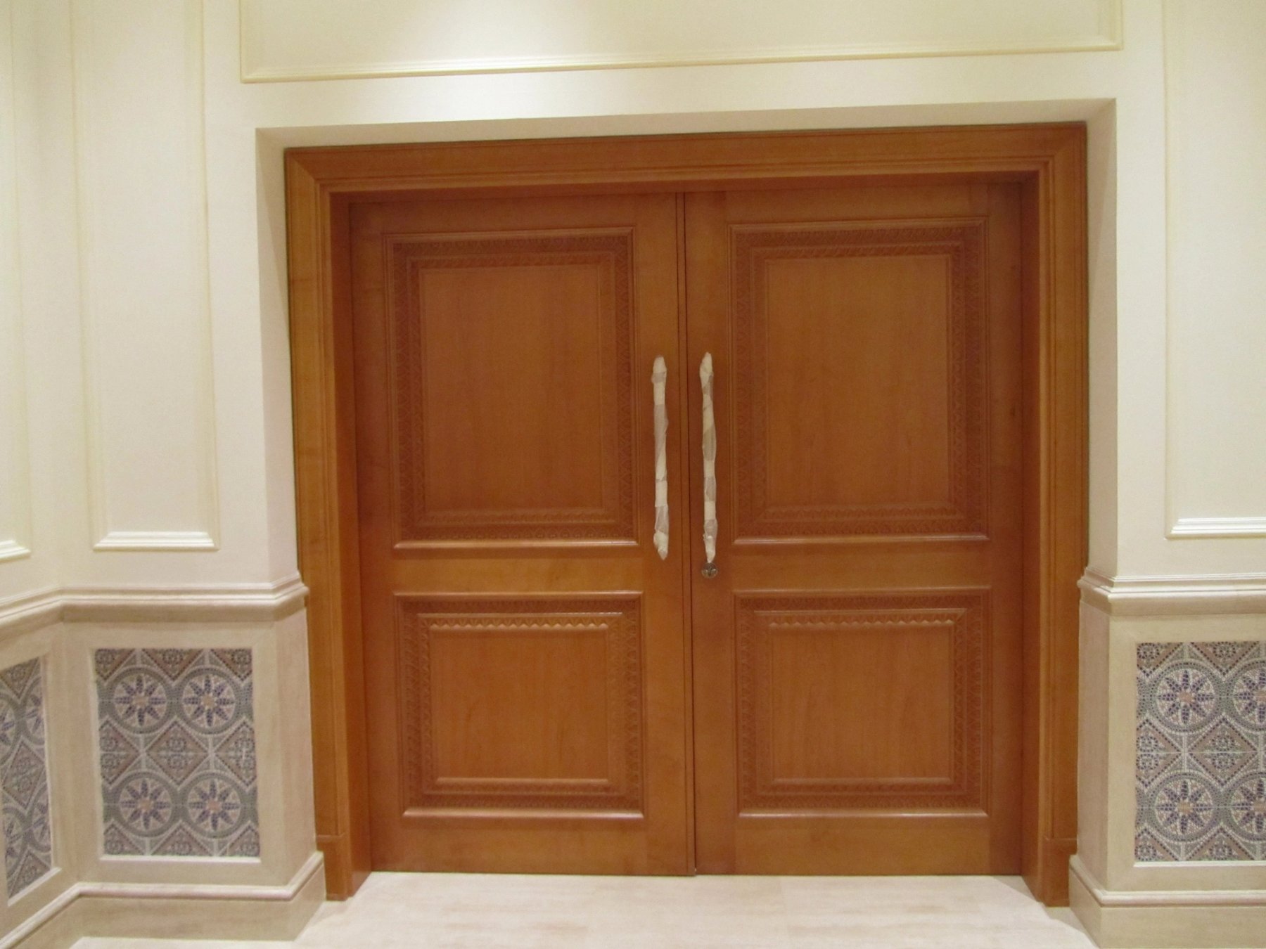 Bespoke timber double doors framed by decorative wall panelling and patterned tiles