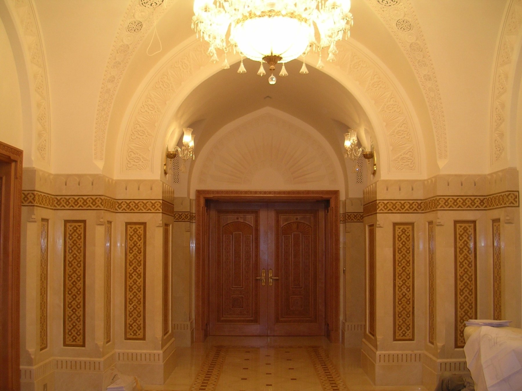 Arched interior passage with timber doors and patterned decorative wall panels