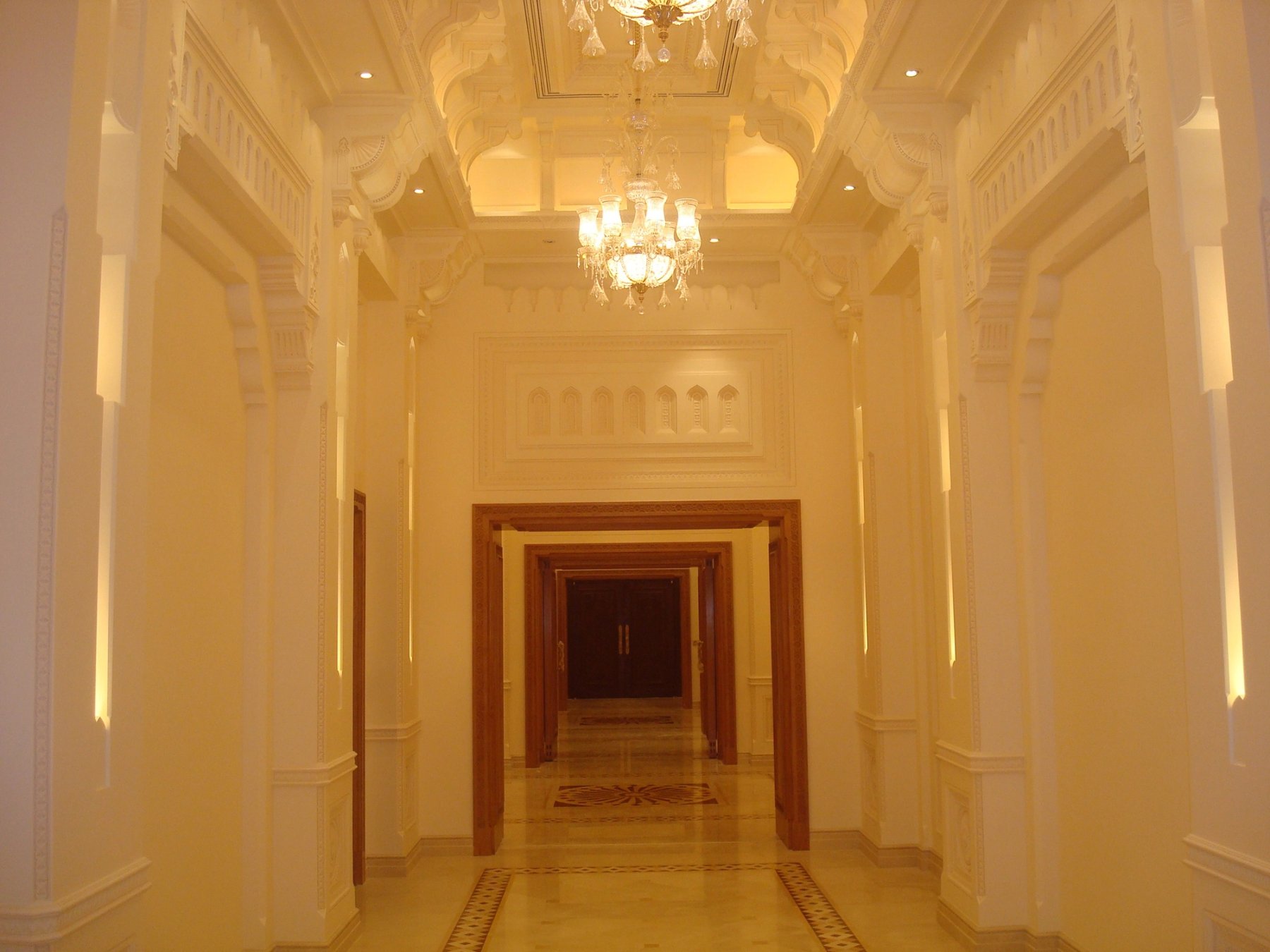 Formal interior corridor with layered plaster detailing and chandelier lighting