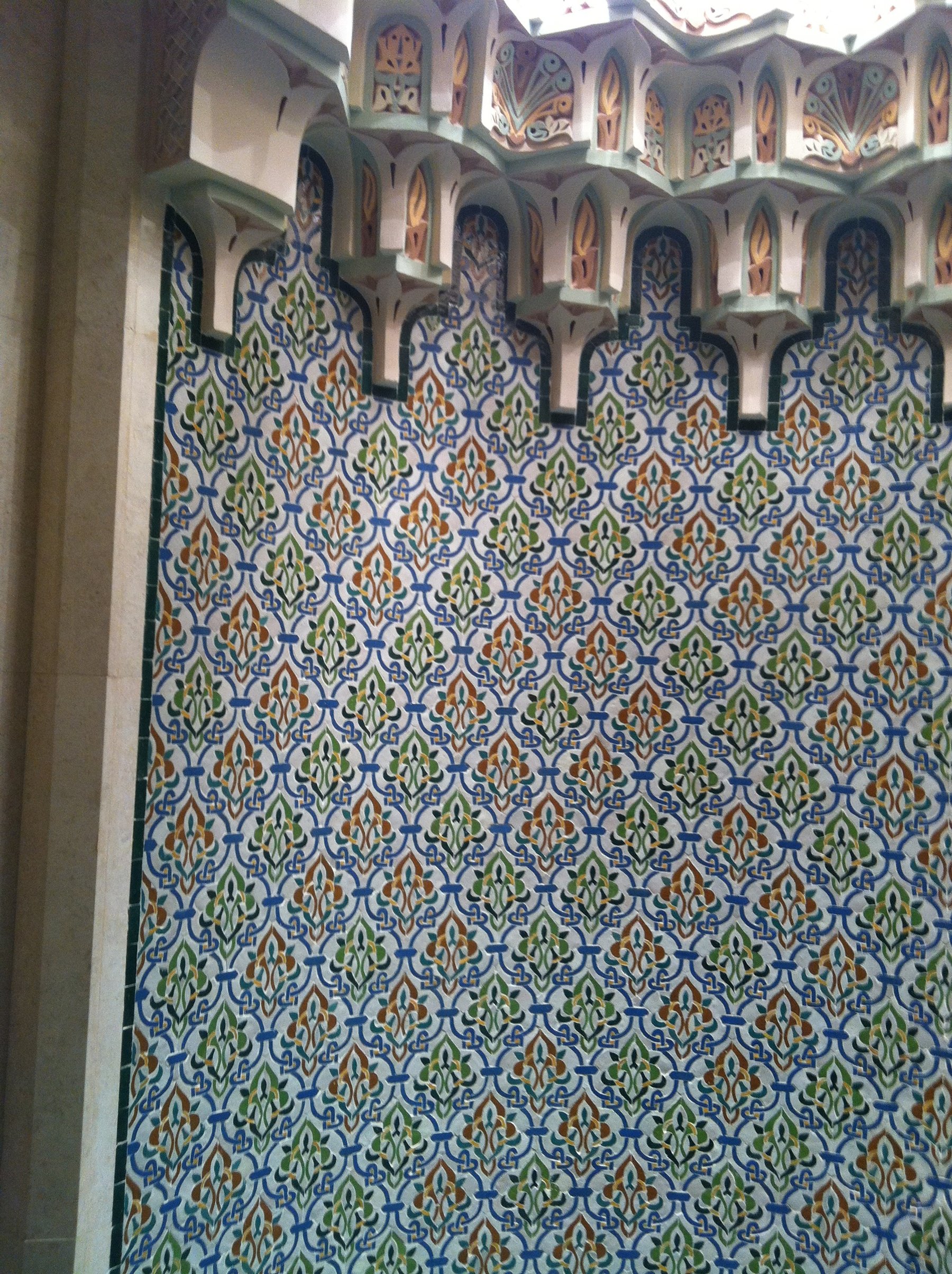 Close-up of patterned ceramic wall detailing beneath carved architectural ornament