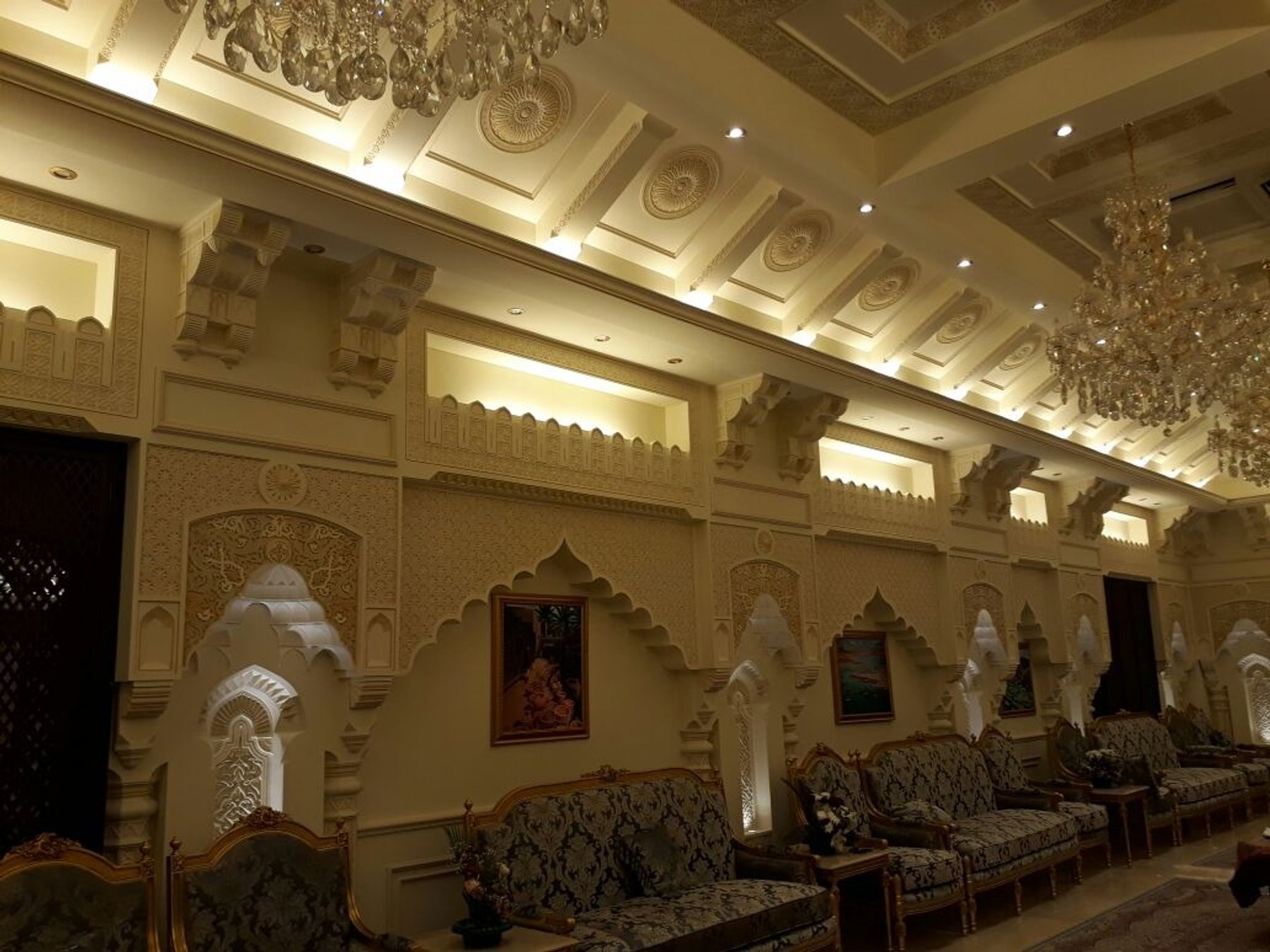 Formal seating area with decorative wall panels, carved arches and chandelier lighting