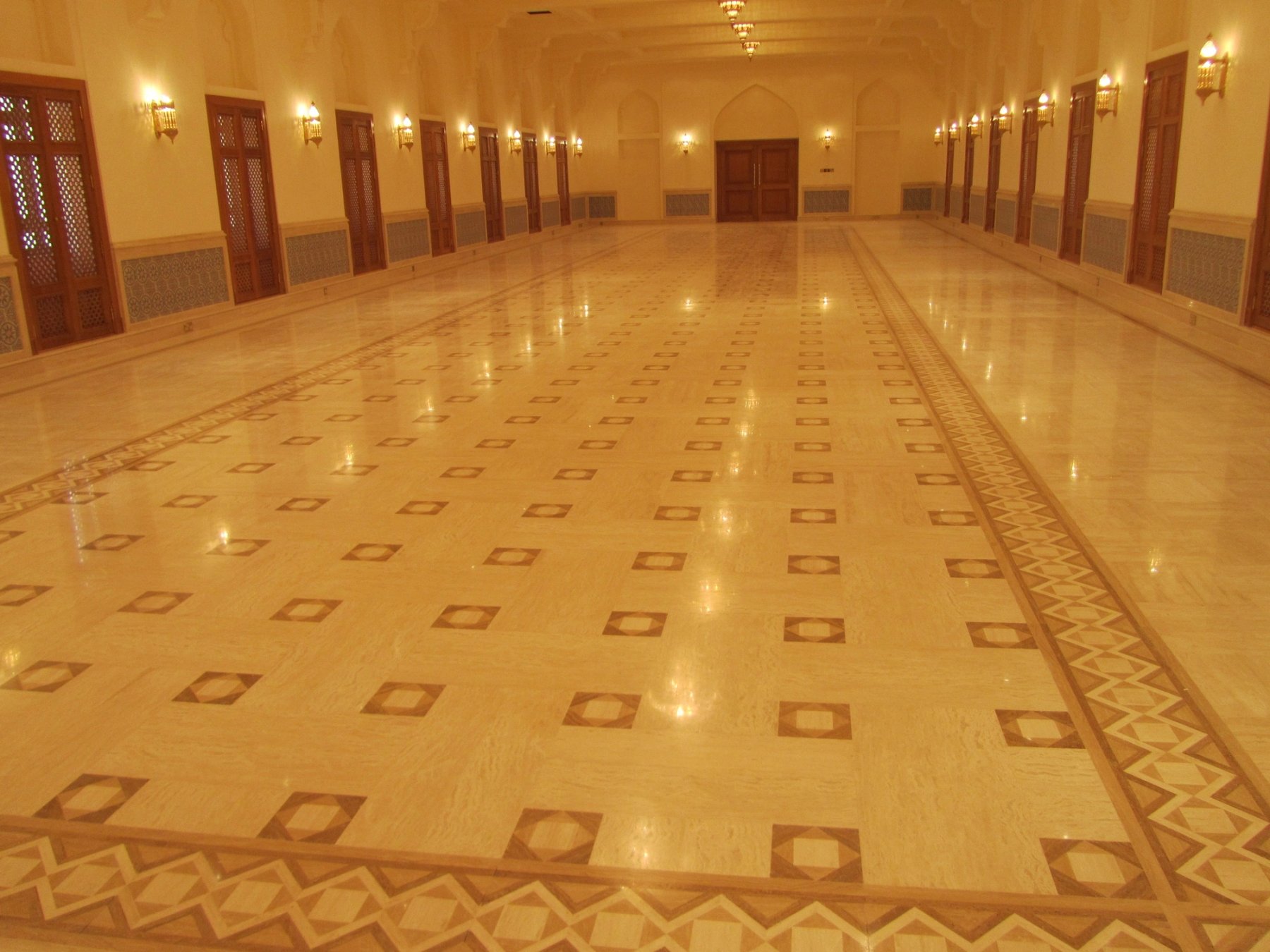 Large private interior hall with repeated timber lattice doors and patterned stone flooring