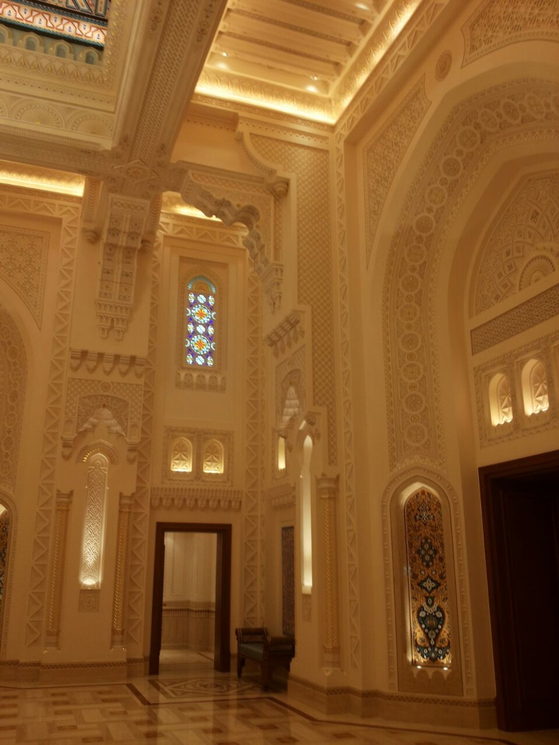 Ornate interior corner with stained glass, carved plasterwork and illuminated arches