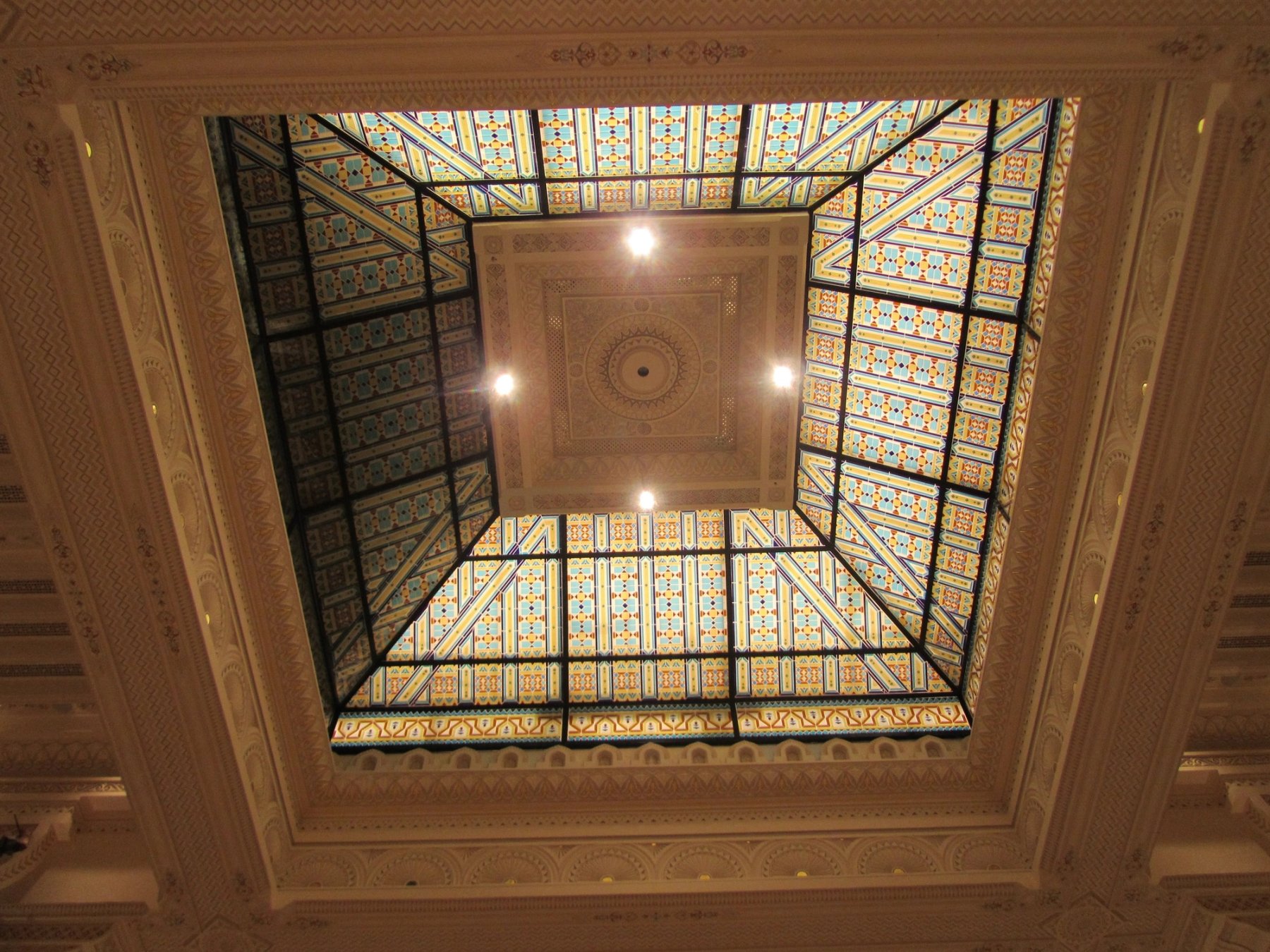 Stained-glass ceiling feature framed by layered architectural mouldings