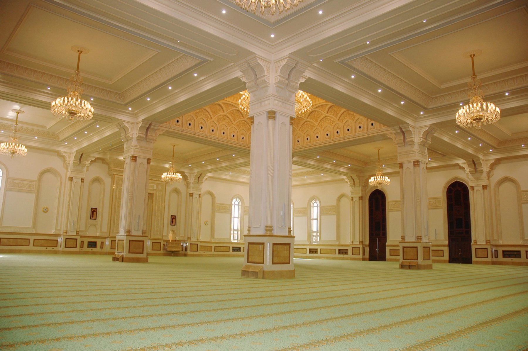 Wide prayer hall with detailed columns, ceiling mouldings and chandeliers