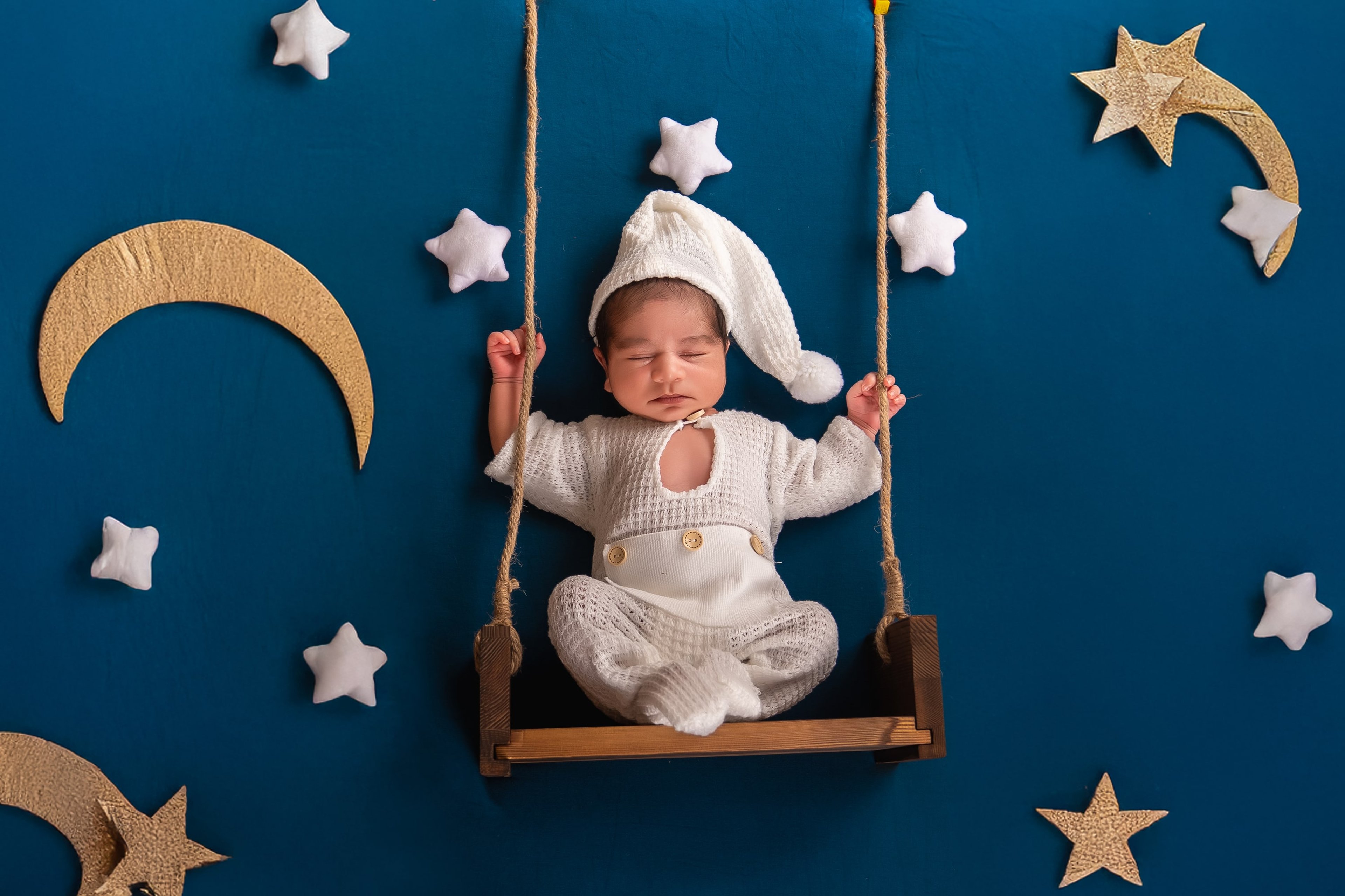 Newborn on a little swing under moon and stars